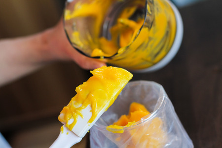 Holding white spatula with orange cream ready to add into piping bagの写真素材