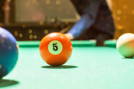 In this photo you can see a boy ready to hit the orange pool ball number 5
