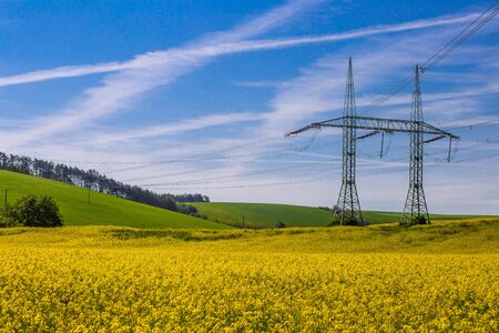 High-voltage power transmission towers over farm fieldsの写真素材