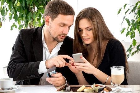 Young couple paying by smart phone for ther order at the restaurant