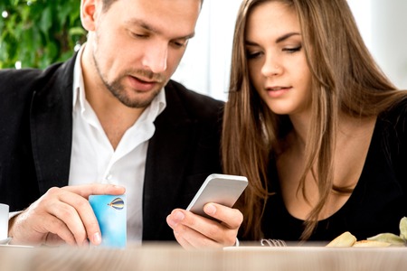 Young couple paying by smart phone for ther order at the restaurantの写真素材