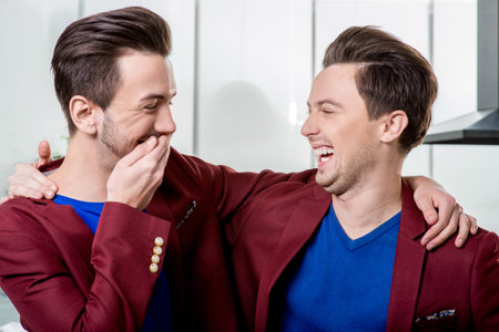 Two friendly brothers twins in red jackets and blue sweater together having fun in the dinner room...