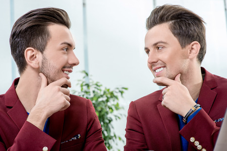 Two friendly brothers twins in red jackets watching one another on white backgroundの写真素材