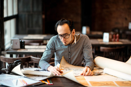Creative architect projecting with pencil on the big drawings in the dark loft office or cafe