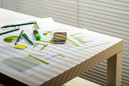 Image of an office desk with financial documents, charts and digital gadgets