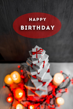 A pile of gift boxes with red ribbons on wooden background with greeting text. Greeting card conceptの写真素材