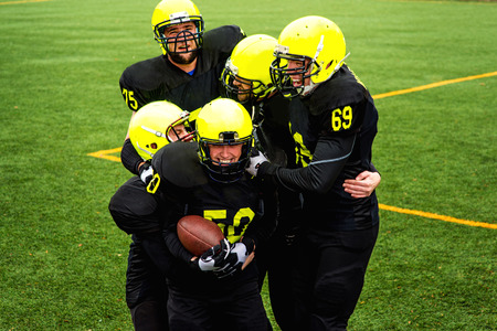 Men in green sportswear and helmet playing american football on the sports groundの写真素材