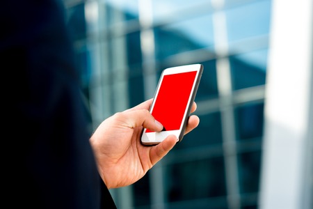 Businessman holding cellphone with empty screen on the contemporary backgroundの写真素材