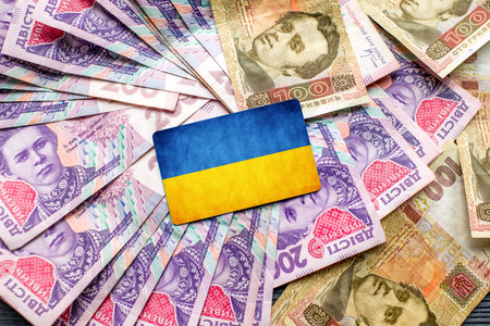 Pile of ukrainian money and ukrainian flagの写真素材