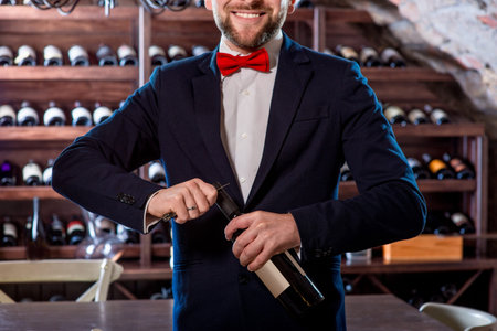 Sommelier opening wine bottle in the wine cellar