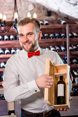 Sommelier showing wooden wine box with expensive wine in the wine cellarの写真素材