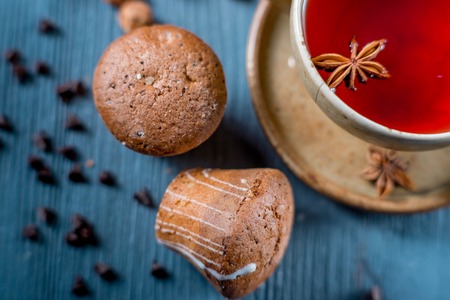Sweet cookies and a cup of red tea with seasonings on blue wooden tableの写真素材