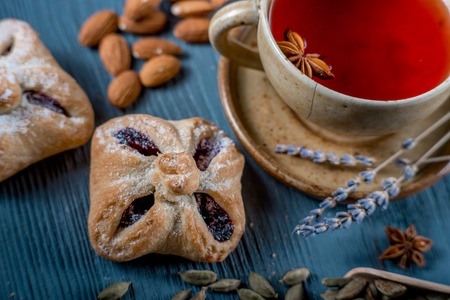 Sweet cookies and a cup of red tea with seasonings and lavender on blue wooden tableの写真素材