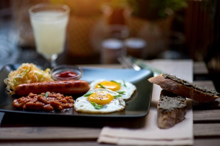 English breakfast with eggs, beans, sausage and lemonade on wooden table with blurred backgroundの写真素材