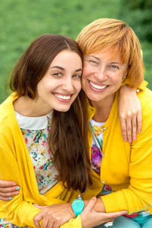 Mother with her daughter smiling and hugging dressed in yellow in the park