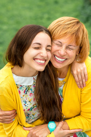 Mother with her daughter smiling and hugging dressed in yellow in the park