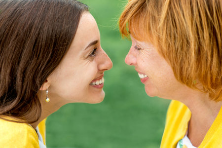 Mother with her daughter smiling and hugging dressed in yellow in the park