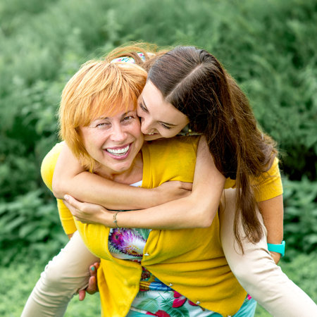 Mother giving piggyback riding to her daughter in the park