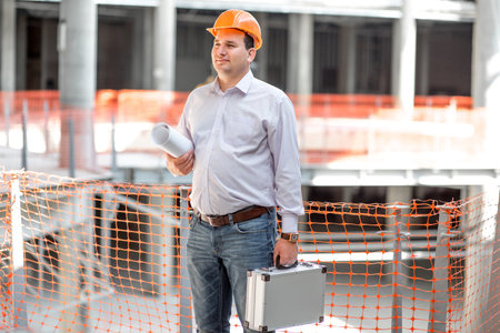 A foreman with drawings and case supervising the project at the construction.