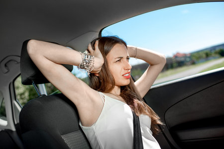 Young sad woman shouts holding his head standing in the car in the traffic