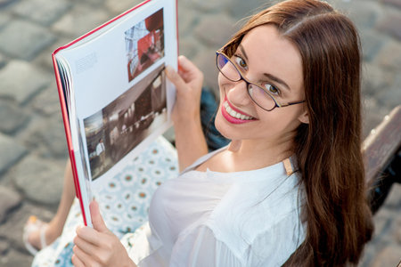 Young beautiful woman reading red book in the city