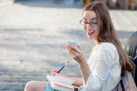 Young wYoung woman sitting and studying on the bench with booksの写真素材