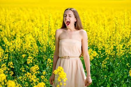 Beautiful happy girl having fun on the colza field. Healthy young woman outdoors. Countryside.