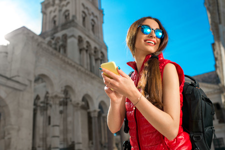Young woman dressed in sportswear with smart phone traveling in the old city center. Traveling application conceptの写真素材