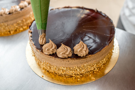 Woman making biscuit cake with nuts and chocolate at the bakeryの写真素材