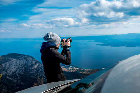 Man photographing lanscapes standing near his car on the top of mountain