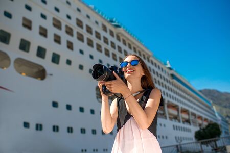 Young woman tourist photographing near the big cruise linerの写真素材