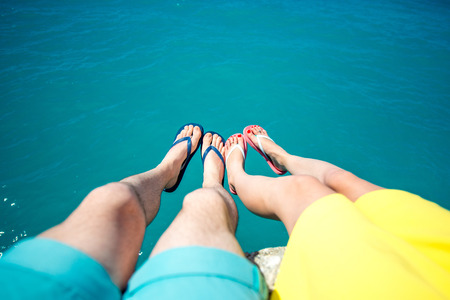 Couples legs together in colorful slippers on the blue sea background with space for your textの写真素材
