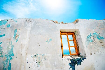 Old window in abandoned house with beautiful view at seaの写真素材