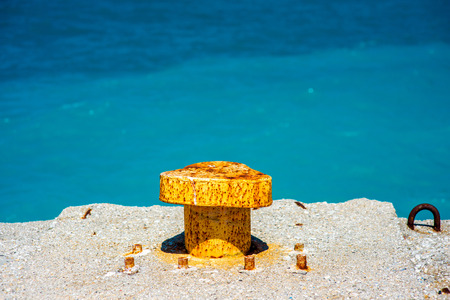 Rusty knecht on the concrete pier with blue water on backgroundの写真素材