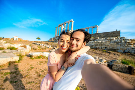 Tourist young couple taking selfie portrait on Poseidon temple background in Sounion, Greeceの写真素材