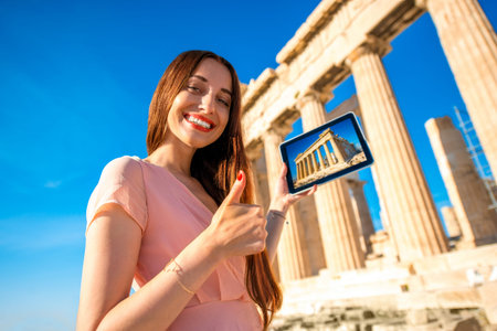 Woman advertising Acropolis with digital tablet near Parthenon templeの写真素材