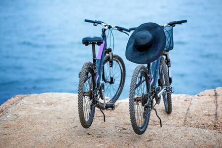 Two bicycles standing on the concrete pier on the blue water backgroundの写真素材