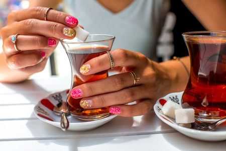 Woman holding turkish tea in traditional teacup and limpet in the restaurantの写真素材