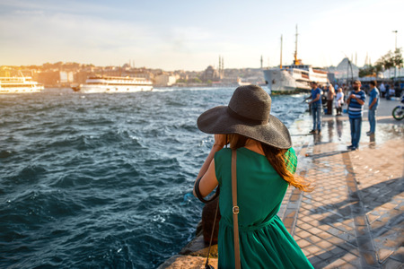 Young woman traveler in green dress and hat enjoying great view of the Bosphorus in Istanbulの写真素材