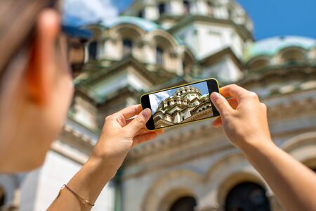Woman tourist photographing with smart phone the St. Alexander Nevsky Cathedral in Sofia, the capital of Bulgariaの写真素材