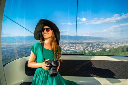 Young woman tourist sitting in cable car on the way to the top of Vodno mountain near Skopje city in...