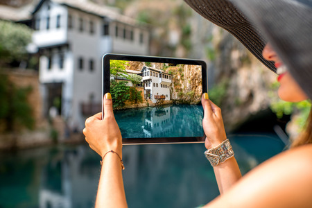 Female tourist photographing with digital tablet house on Buna spring in Blagaj village in Bosnia and Herzegovinaの写真素材