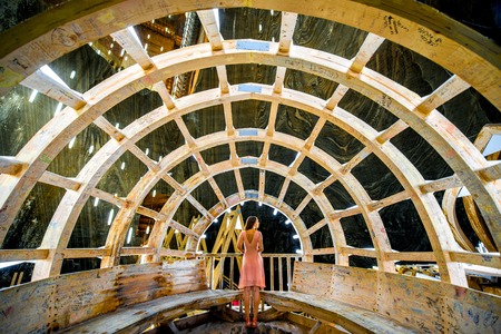 TURDA, ROMANIA - JUNE 30 2015: Young female tourist at illuminated instalation in the Salt Mine Salina Turda museum in Romaniaのeditorial素材