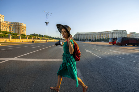 Young woman traveler running with backpack and photo camera in the center of Bucharest cityの写真素材