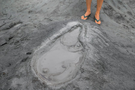 Mud volcano and man's feet near the craterの写真素材