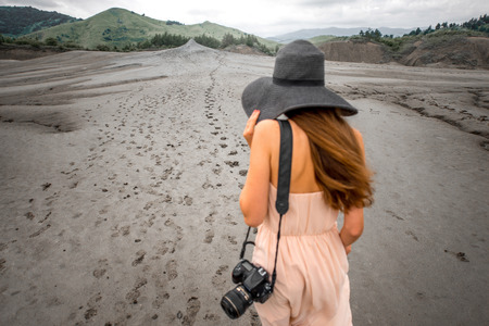 Young female traveler with photocamera walking near mud volcanoes in Buzau in Romaniaの写真素材