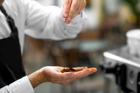 Barista powdering coffee on his hand, checking the quality of coffee. Close up view focused on handsの写真素材