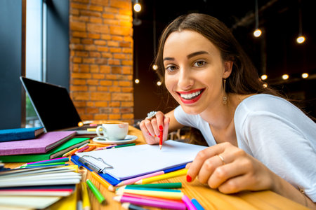 Playful and persistent girl studing with colorful stuff in the modern cafe interiorの写真素材