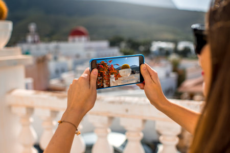 Young female traveler photographing with phone Agaete city on Canary island