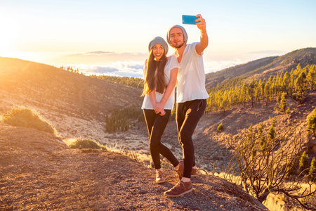 Young couple dressed alike in white t-shirt and hat taking selfie photo with smart phone